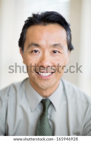 Portrait of confident Asian male cancer specialist smiling in hospital