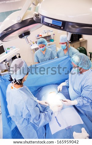 High angle view of surgeons operating patient in surgical theater