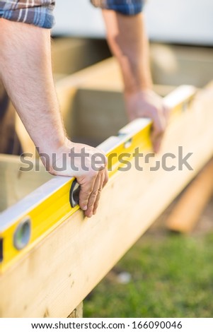 Closeup of carpenter\'s hands checking level of wood at construction site