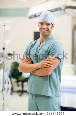Portrait of smiling surgeon standing arms crossed in operation room