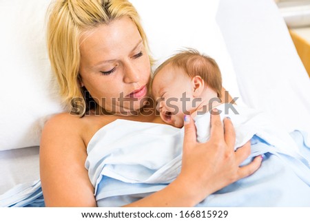 Loving young mother practising kangaroo mother care (skin to skni contact)