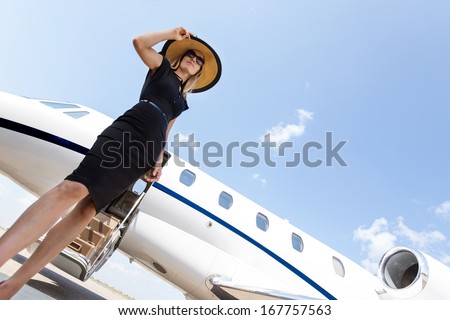 Low angle view of woman in elegant dress standing in front of private jet against sky
