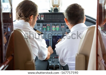 Rear view of pilot and copilot in private jet cockpit
