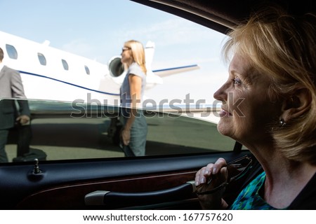 Thoughtful mature businesswoman in car looking at private jet