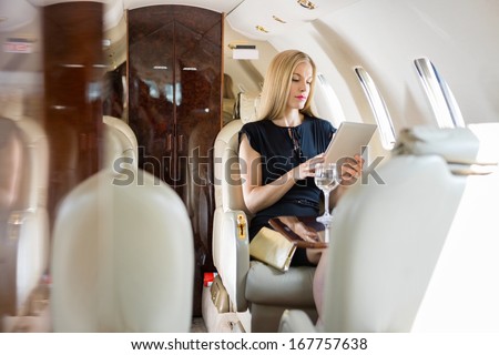 Rich Mid Adult Woman Using Tablet Computer In Private Jet