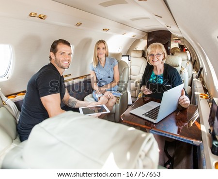 Portrait of business people having discussion over laptop on private jet