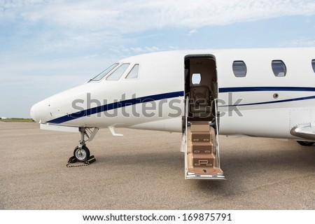 Business jet with open door parked at terminal