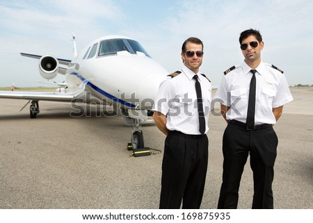 Portrait of confident pilots standing in front of private jet