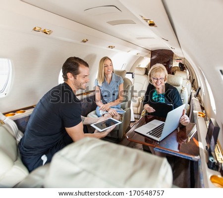 Business people having discussion over laptop on private jet