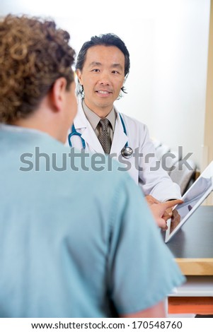 Mature doctor and nurse using digital tablet at hospital reception