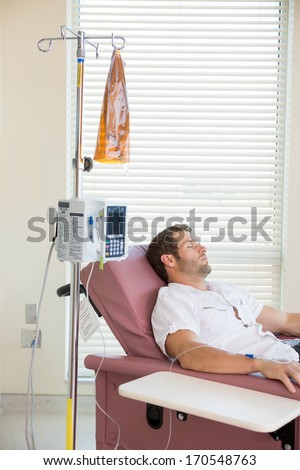 Male patient sleeping while receiving chemotherapy in hospital room