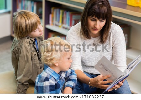 Young Teacher Reading Book For Students In School Library