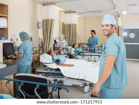 Portrait Of Young Male Nurse Standing In Hospital Par Unit