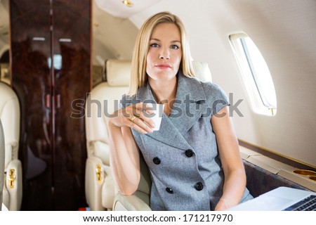 Portrait of confident businesswoman having coffee in private jet