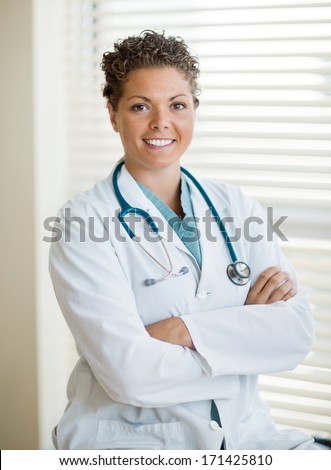Portrait of confident cancer specialist in labcoat with arms crossed sitting at clinic