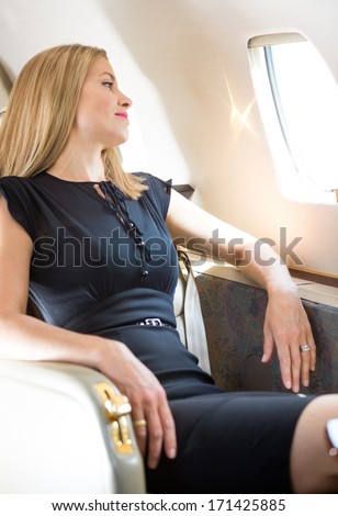 Attractive Rich Woman Looking Through Window In Private Jet