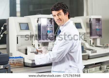 Portrait of confident male scientist using urine analyzer to test samples in medical lab