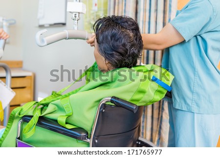 Cropped image of female nurse holding hydraulic lift\'s handle with patient on wheelchair in hospital