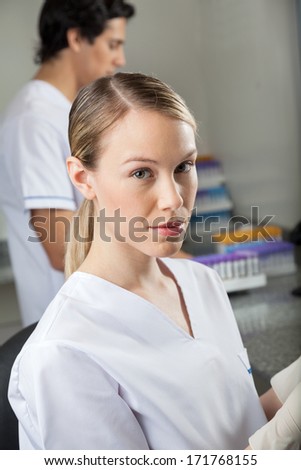 Portrait of female lab technician with colleague in background
