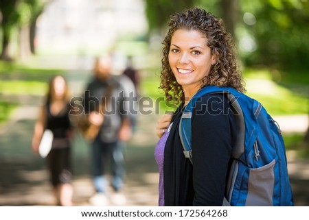 Side view portrait of confident female grad student with backpack standing at campus