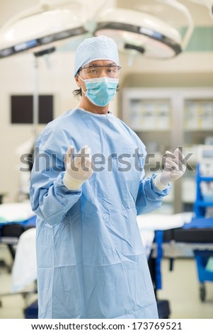 Portrait of mid adult surgeon in surgical gown standing in operation room