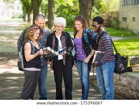 Group of multiethnic students discussing notes on campus road