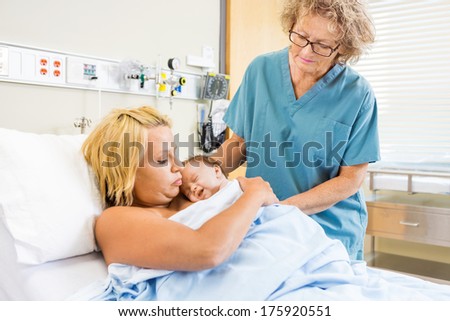 Nurse assisting young mother with kangaroo mother care (skin to skin contact)