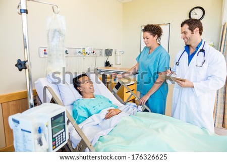Mature male patient looking at medical team standing by in hospital room