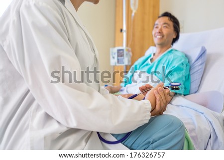 Cropped image of female doctor sitting with patient on bed in hospital