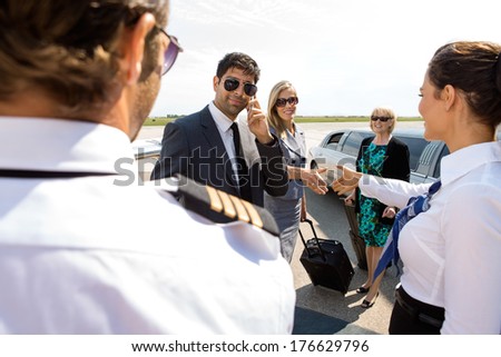 Corporate man and women greeting pilot and airhostess at airport terminal