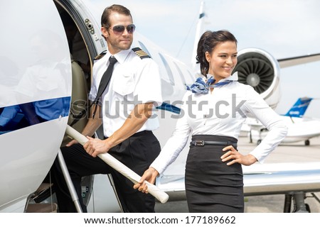 Beautiful airhostess with pilot boarding private jet