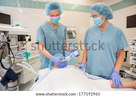 Female nurses putting oxygen mask on patient in operation room