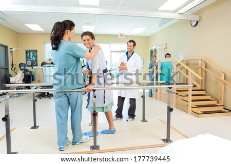 Portrait of female patient being assisted by physical therapist while doctor applauding