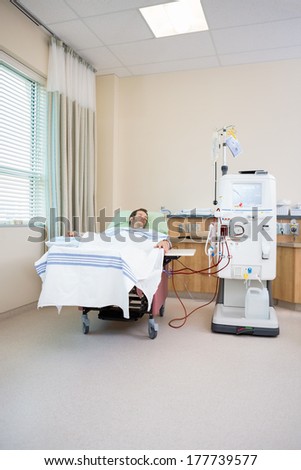 Young male patient sleeping while receiving renal dialysis in hospital room