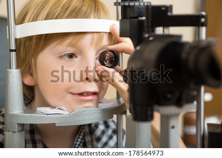 Closeup of male optician\'s hand checking boy\'s eye with lens in store