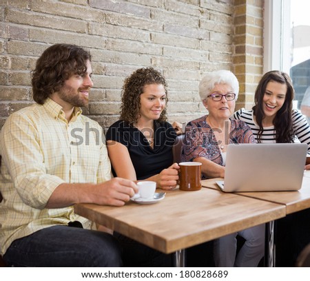 Senior woman with friends using laptop at table in cafe