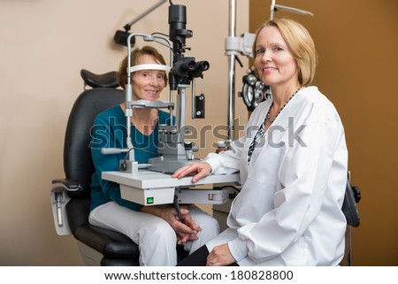 Portrait of female optometrist examining senior patient\'s eyes with slit lamp in eye clinic