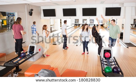 Group of happy friends playing in bowling alley