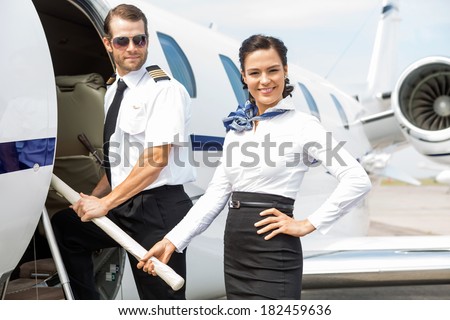 Portrait of beautiful airhostess with pilot boarding private jet