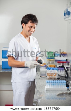 Happy young man scanning barcode on specimen in laboratory