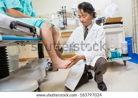 Full length of neurologist examining patient\'s tendon