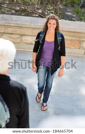 Portrait of confident mid adult student with backpack walking on college campus
