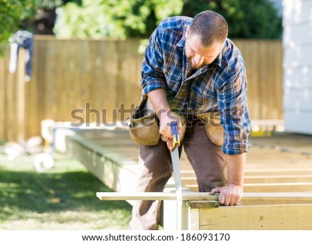 Mid adult worker sawing wood at construction site