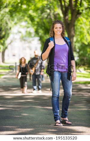 Full length portrait of confident female grad student with backpack standing on campus