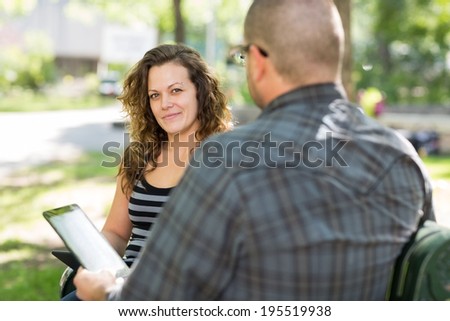 Portrait of confident female university student sitting with male friend at campus