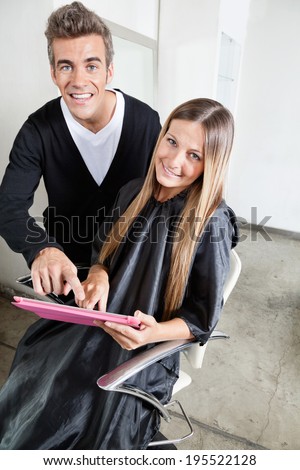 Portrait of male hairdresser and customer using digital tablet in beauty salon