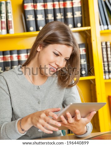 Happy young woman using digital tablet in college library