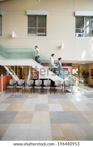 Side view of medical team and patient walking on stairs in hospital