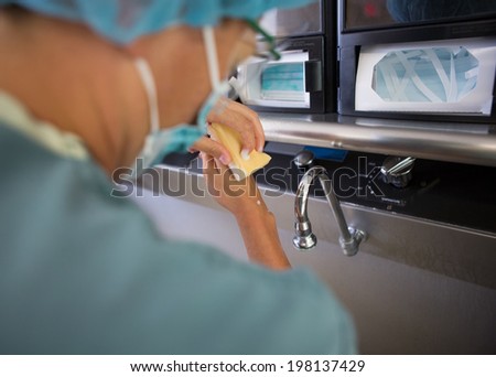 Rear view of female doctor washing hands before surgery in hospital