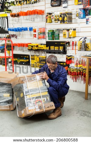 Full length of mature worker lifting tool package in hardware shop
